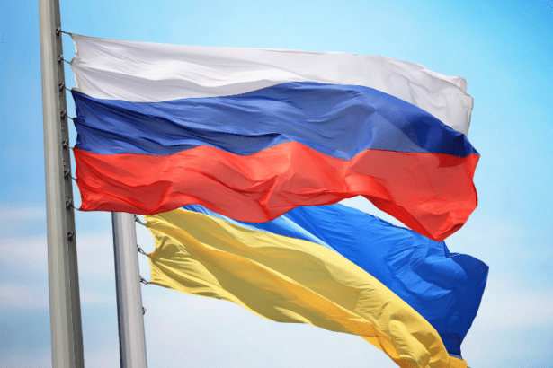 Russian and Ukrainian flags waving against blue sky