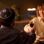 Man in yarmulke toasts woman during a festive Jewish celebration with food.